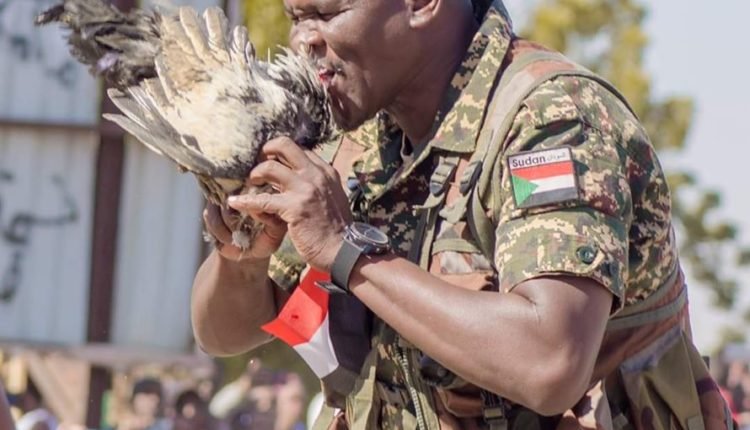 صورة لجندي سوداني يحاول التهام دجاجة حية، في احتفال تغيير الحرس الجمهوري